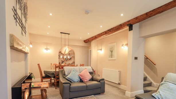 A cozy living room with a sofa, a dining table, and a staircase. - Bottle Tops (Windermere)