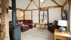Una sala de estar acogedora con una chimenea de leña, sofás de cuero, una mesa de centro de madera y una mesita auxiliar con lámpara.