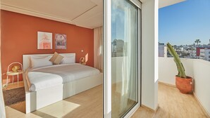 A modern bedroom with a large bed, a glass door leading to a balcony, and a city view. - StayHere Rabat - Hassan Heritage (Rabat)