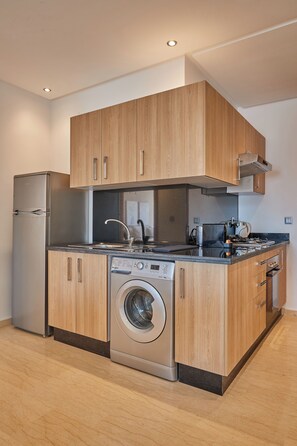 Una cocina moderna con armarios de madera, un refrigerador de acero inoxidable, una lavadora y una estufa.