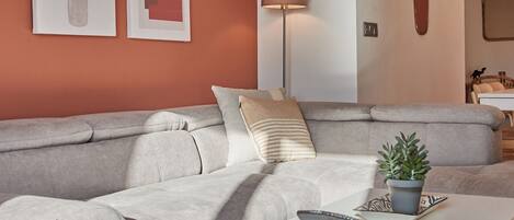A modern living room with a grey sofa, a white coffee table, and a patterned rug.