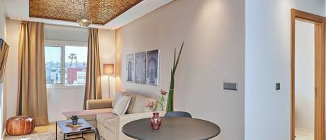 A modern living room with a round table, a sofa, and a decorative ceiling.
