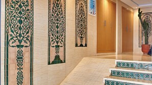 A hotel corridor with ornate wall designs, wooden doors, and a staircase with patterned steps. - StayHere Rabat - Hassan Heritage (Rabat)