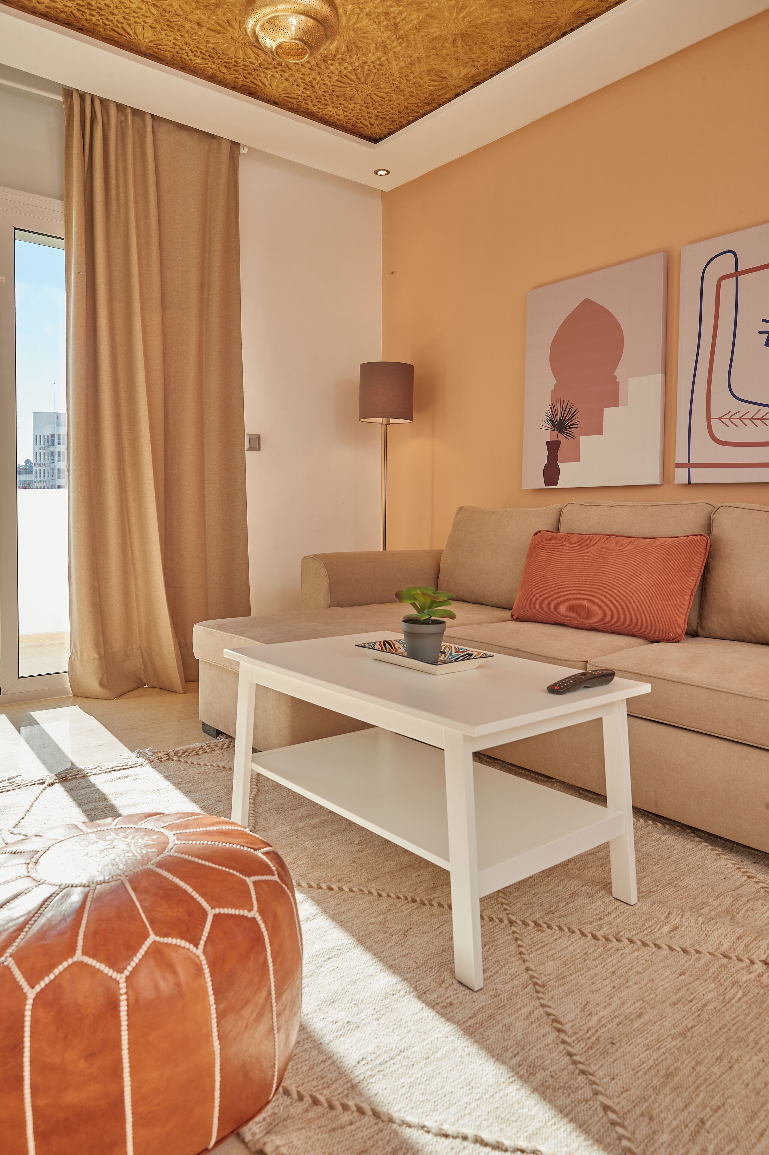 A modern living room with a sofa, a coffee table, a rug, and a large window with curtains.