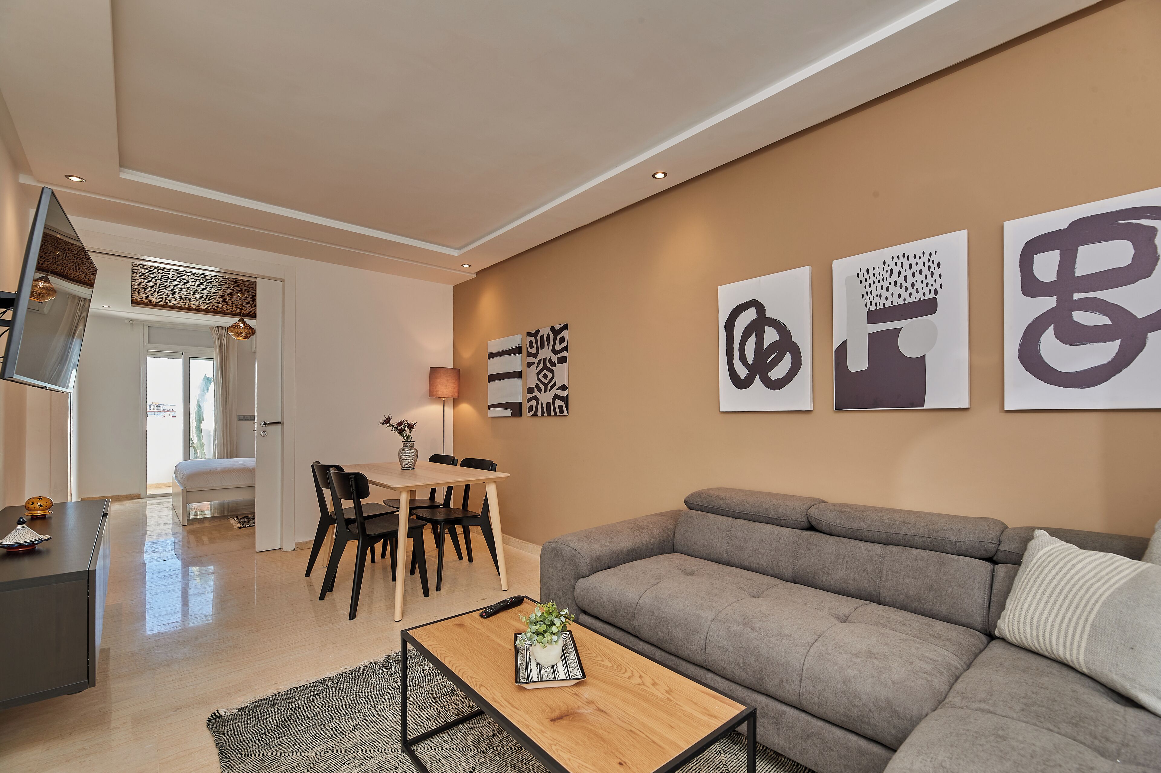 A modern living room with a grey sofa, a coffee table with a plant, and abstract wall art.
