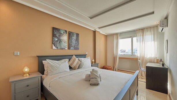 A modern hotel room with a large bed, a nightstand, a desk, and a window with curtains. - StayHere Rabat - Hassan Heritage (Rabat)