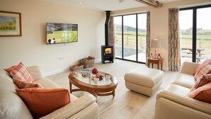 A spacious living room with a large TV, a fireplace, and a view of the outdoors. - A beautiful barn conversion sleeping four guests. (Acton Burnell, Shrewsbury)