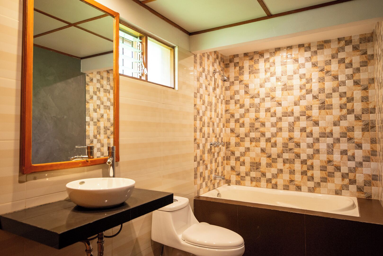 Un baño con pared de baldosas a cuadros, un lavamanos blanco y una bañera.