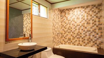 Un baño con pared de baldosas a cuadros, un lavamanos blanco y una bañera.