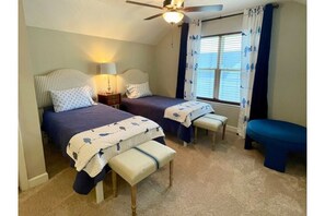 Two single beds with matching benches, a ceiling fan, and a nightstand with a lamp.