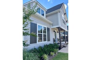 Stunning two-story residence with a modern design, featuring a white window and a well-manicured lawn.