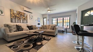 A modern living room with two sofas, a coffee table, and a dining area with a chair and table. - Sea Turtle Condo 2 Bdr-2 Bth in Palm Beach Area, walking distance to the beach. (Noord)