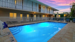 A hotel with a swimming pool, multiple balconies, and a sunset view.