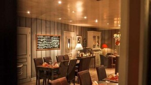A restaurant with a long table and chairs, a menu board, and a lamp. - Le Cottage Hotel (Bruay-la-Buissiere)