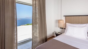 A hotel room with a bed, a nightstand, a lamp, and a view of the sea. - Sunset Plaka (Milos)