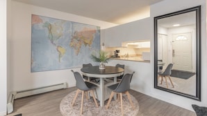 A dining area with a round table, chairs, a world map, and a large mirror.
