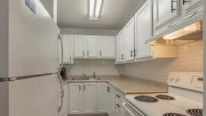 A kitchen with white cabinets, a stove, and a sink.