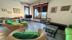 A spacious living area with wicker furniture, a glass coffee table, and large windows offering a view of the outdoors. - ML in sea promenade (Chiavari)