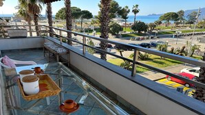 A balcony with a glass table, wicker tray, and a bench. - ML in sea promenade (Chiavari)