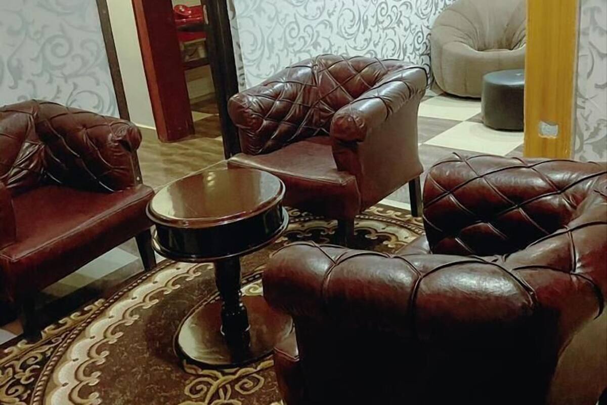 Un salon avec des fauteuils en cuir, une table basse ronde et un tapis à motifs.