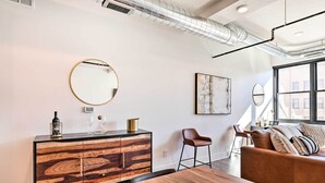 Un salon moderne avec une table à manger en bois, un canapé en cuir, un miroir rond et un meuble en bois doté de tiroirs.