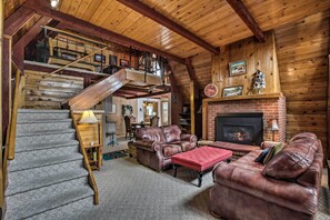 Cozy living area with a grand staircase, fireplace, and comfortable seating.