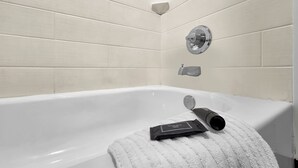 A white bathtub with a towel and a bottle.