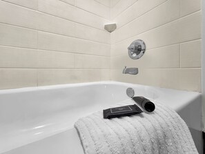 Eine weiße Badewanne mit Handtuch und Flasche.