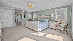 A bedroom with a bed, a chair, a nightstand, a dresser, and a ceiling fan.