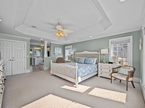 Ein Schlafzimmer mit einem Bett, einem Sessel, einem Nachttisch, einer Kommode und einem Deckenventilator.
