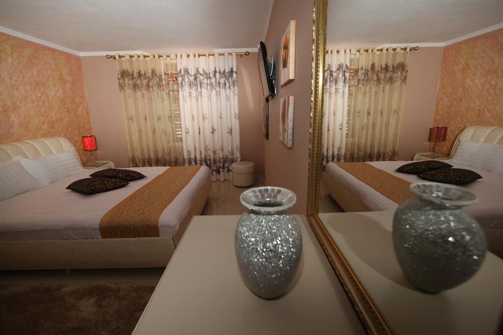 Ein Hotelzimmer mit zwei Betten, einem großen Spiegel und dekorativen Vasen.