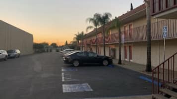 A street view with a row of two-story buildings, parked cars, and a clear sky.