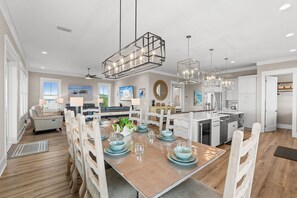 A spacious dining area with a wooden table set for four, surrounded by white chairs.