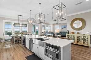 A modern kitchen with stainless steel appliances, a large island, and pendant lighting.