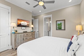 A bedroom with a bed, a television on the wall, a dresser, and a ceiling fan. - A Weekend at Billys: 5 Bedrooms, Private Pool, Pet Friendly, Plantation! (St. George Island)