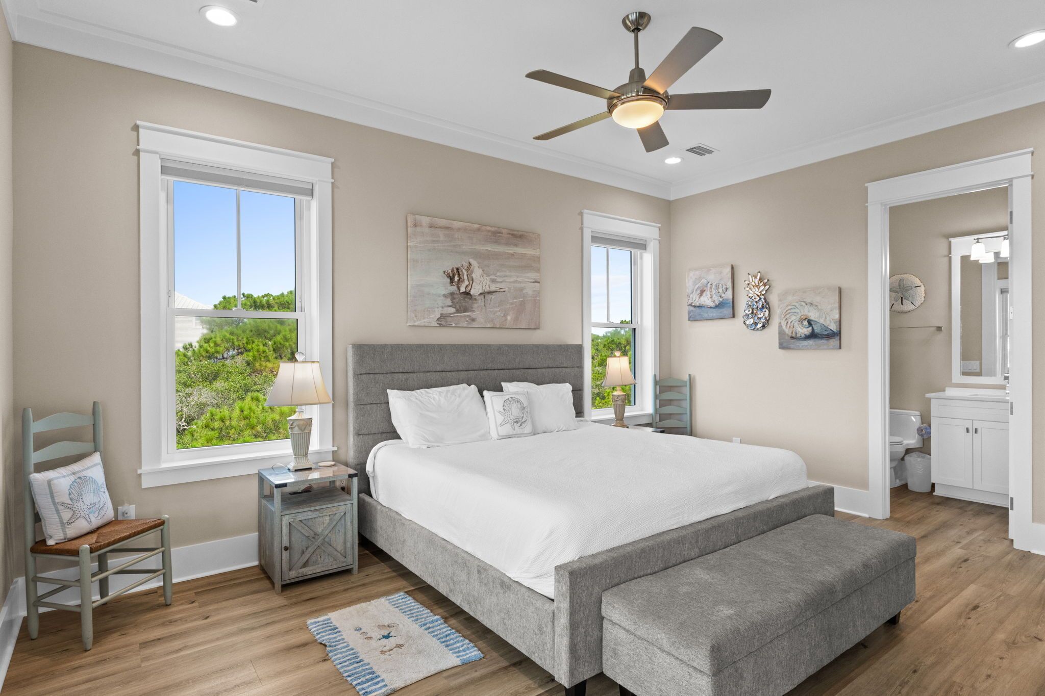 A bedroom with a bed, bedside tables, a chair, a window, and artwork on the walls.
