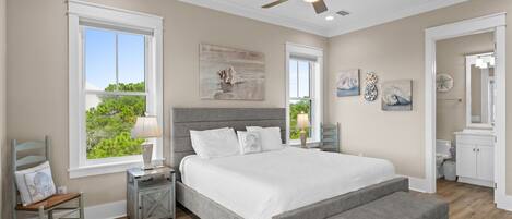 A bedroom with a bed, bedside tables, a chair, a window, and artwork on the walls.