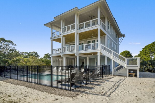 A multi-story building with a pool, outdoor seating, and a staircase leading to the upper levels.