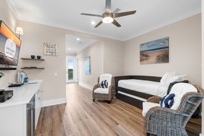 A bedroom with a bed, a chair, a desk, a ceiling fan, and a painting on the wall. - A Weekend at Billys: 5 Bedrooms, Private Pool, Pet Friendly, Plantation! (St. George Island)