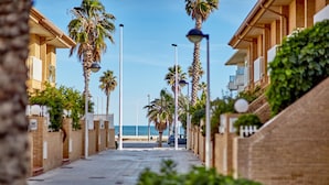 A coastal street lined with palm trees and buildings, leading to the sea. - Patacona Sunrise Duplex I. Wifi + parking + pool + paddle (Alboraya)