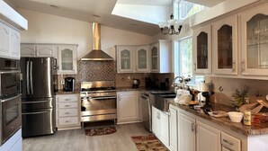 A modern kitchen with stainless steel appliances, white cabinetry, and a skylight. - SERENITY AWAITS HILL WINE Co#2 (Temecula)