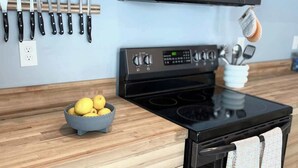 A kitchen with wooden cabinets, a black microwave, a stove, and a bowl of lemons. - Dune View at Silver Lake (Mears)