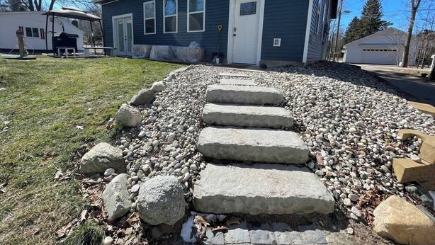 A house with a stone pathway leading to the front door, surrounded by a gravel area. - Dune View at Silver Lake (Mears)