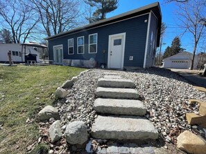 A house with a stone pathway leading to the front door, surrounded by a gravel area. - Dune View at Silver Lake (Mears)