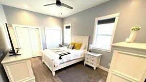 A bedroom with a bed, bedside tables, a nightstand, a dresser, a ceiling fan, and a window. - Dune View at Silver Lake (Mears)