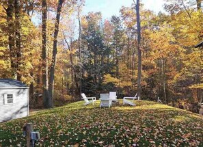 A cabin with a deck, surrounded by trees with autumn foliage. - Dune View at Silver Lake (Mears)