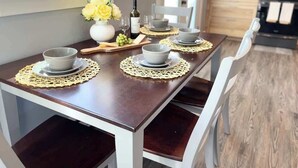 A dining table set with four bowls, a bottle, and a vase with yellow flowers. - Dune View at Silver Lake (Mears)