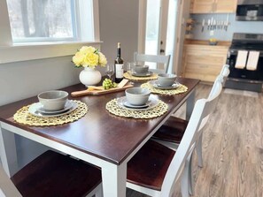A dining table set with four bowls, a bottle, and a vase with yellow flowers.