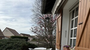 Un patio con suelo de piedra, muebles de plástico blanco y cerca de madera.
