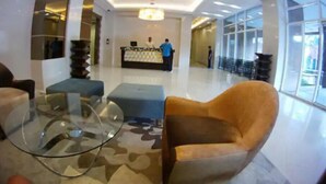 Eine moderne Lobby mit einer Rezeption, einer Sitzecke und großen Fenstern.